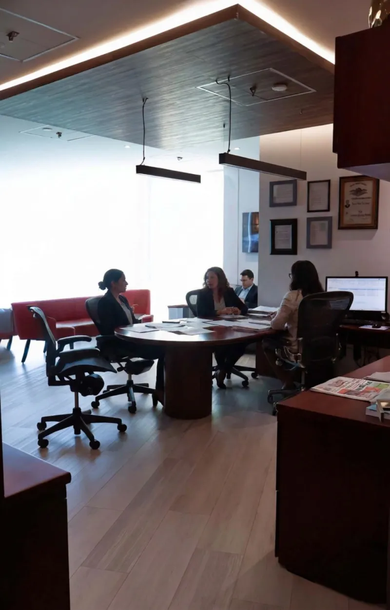 Integrantes del despacho trabajando junto a la pared de reconocimientos profesionales